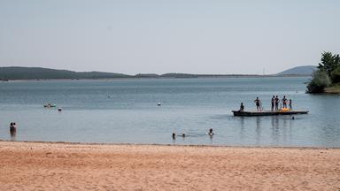  Badegäste sind im Wasser und auf einem schwimmenden Floß
