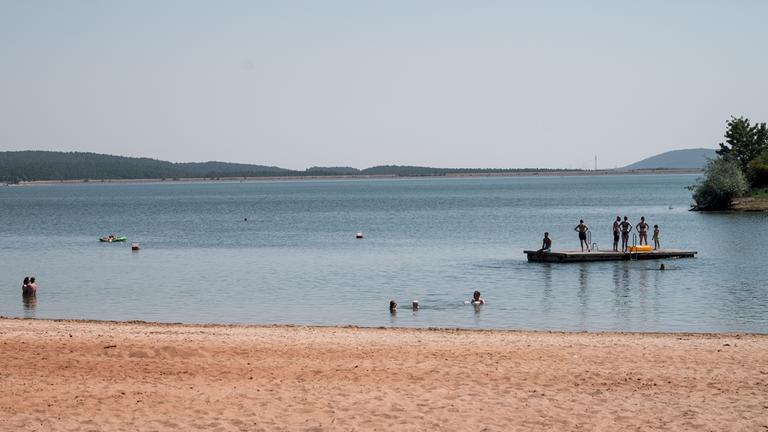  Badegäste sind im Wasser und auf einem schwimmenden Floß