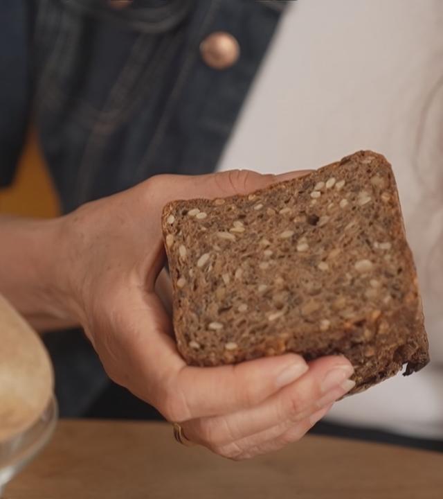 Jemand hält ein Körnerbrot in der Hand.