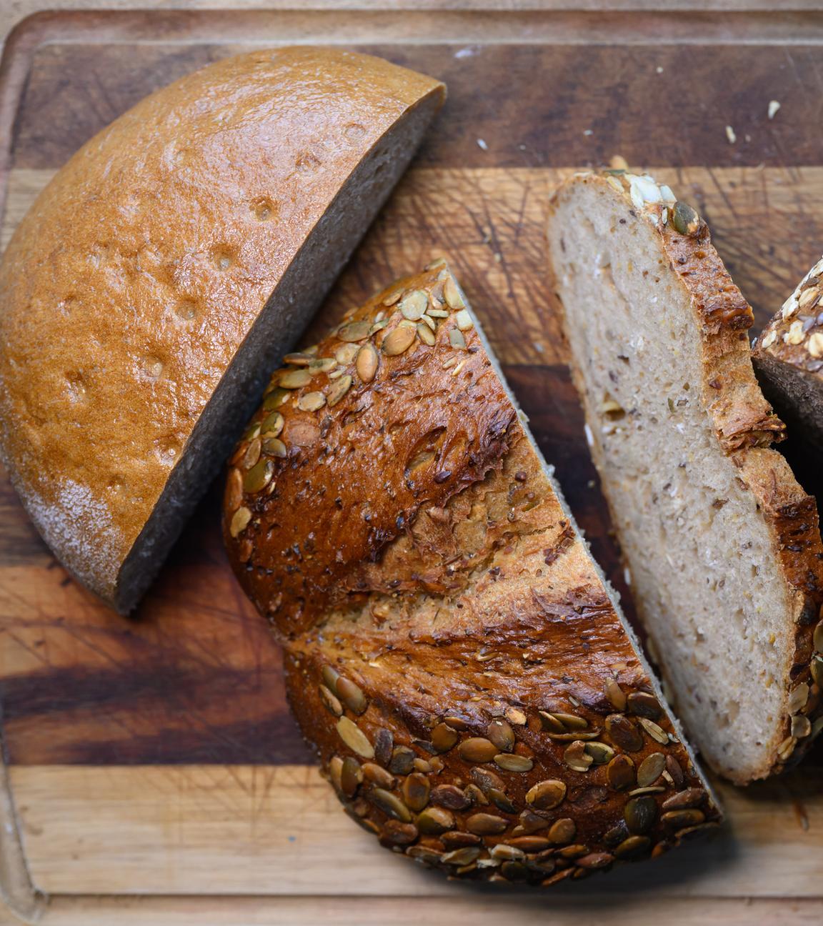 Verschiedene Sorten aufgeschnittenes Brot liegen auf einem Holzbrett.