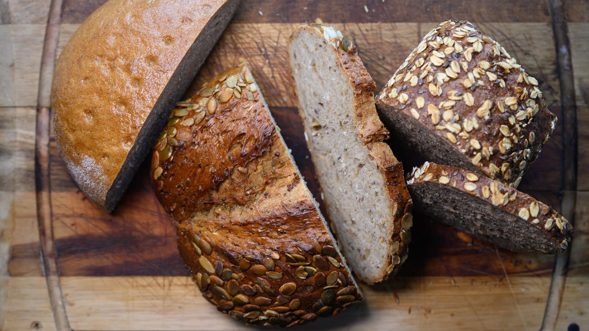 Verschiedene Sorten aufgeschnittenes Brot liegen auf einem Holzbrett.