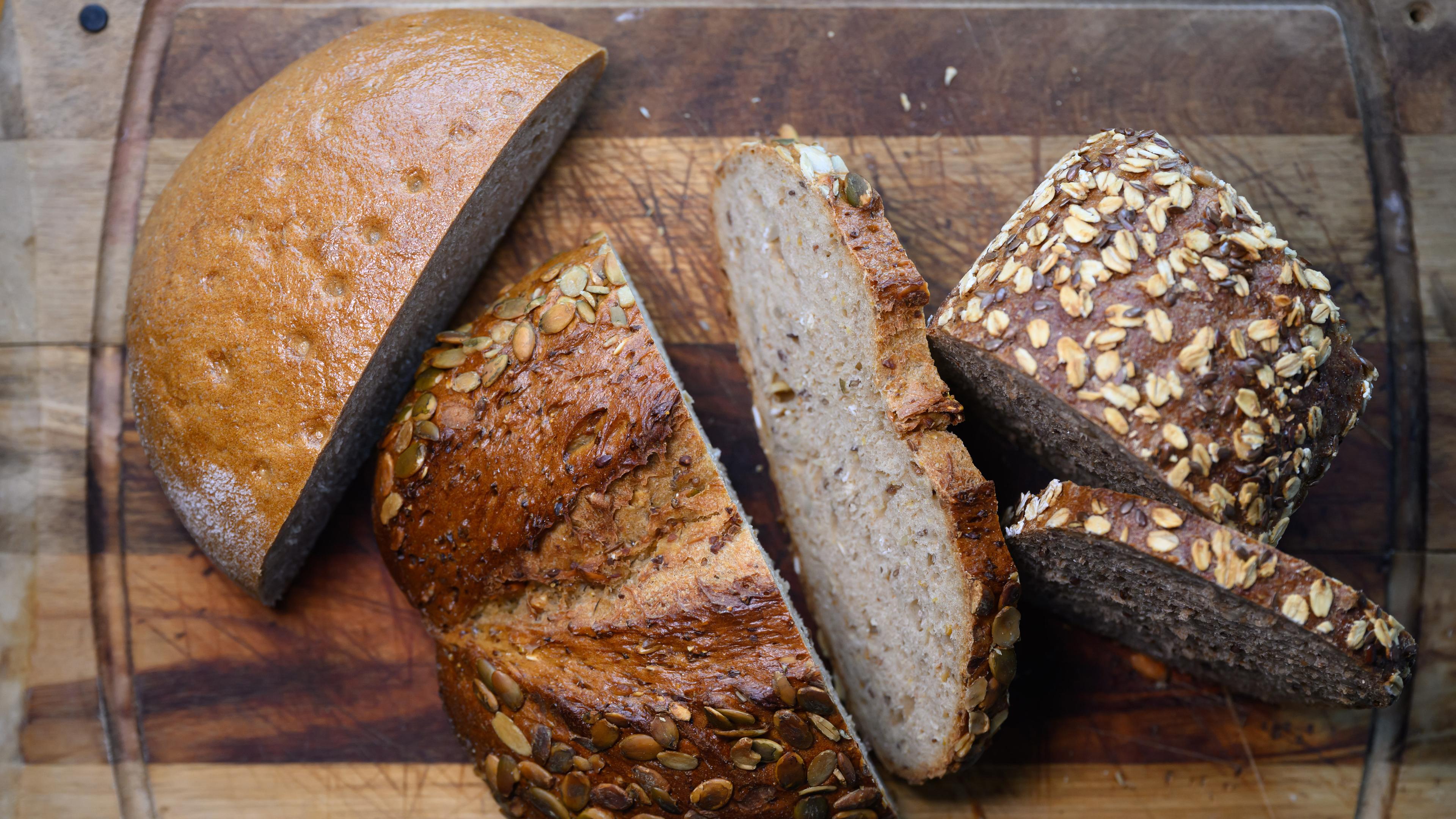 Verschiedene Sorten aufgeschnittenes Brot liegen auf einem Holzbrett.