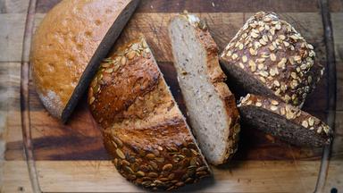 Verschiedene Sorten aufgeschnittenes Brot liegen auf einem Holzbrett.