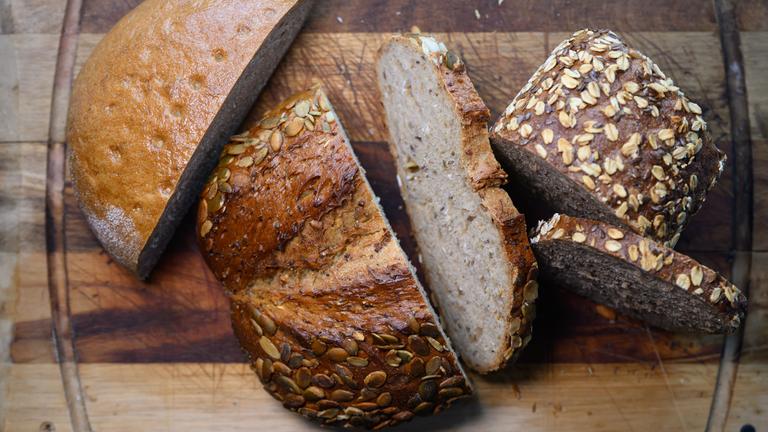 Verschiedene Sorten aufgeschnittenes Brot liegen auf einem Holzbrett.