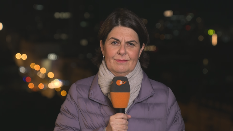 Anne Bruehl mit einem Mikrofon in der Hand und Berlin als Hintergrund.