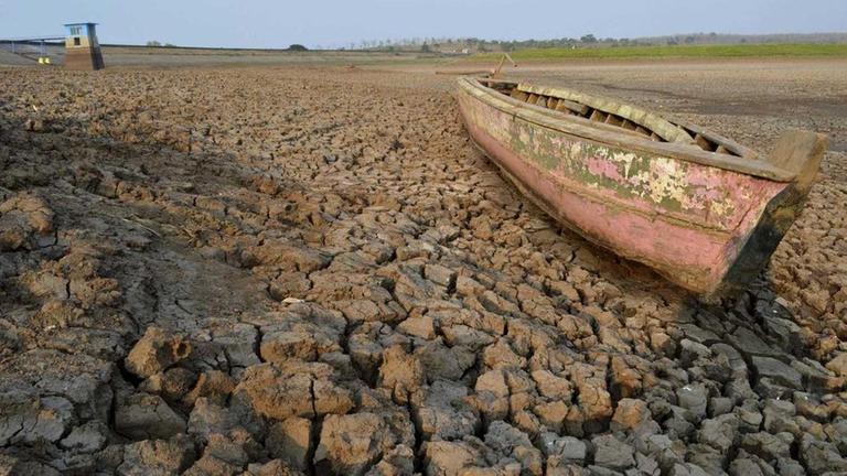 Ein Boot voller Schlamm liegt auf matschigem Untergrund. Die Erde ist aufgerissen.