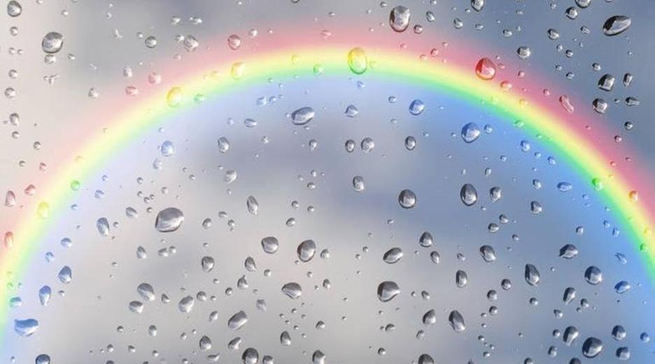 Regenbogen hinter einer Scheibe mit Regentropfen