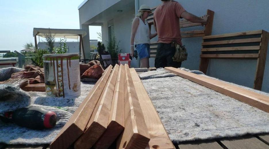 Handwerker, Handwerkerin und Holzlatten auf Balkon