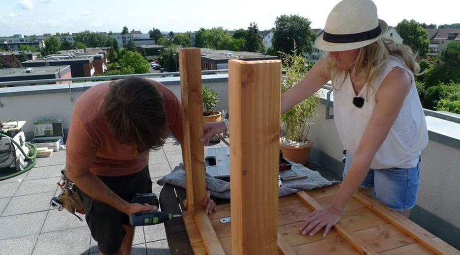 Handwerker und Handwerkerin schrauben an einem Tisch