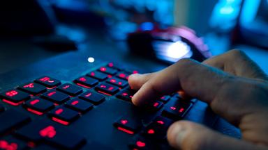 Ein Mann sitzt am Rechner und tippt auf einer Tastatur. 