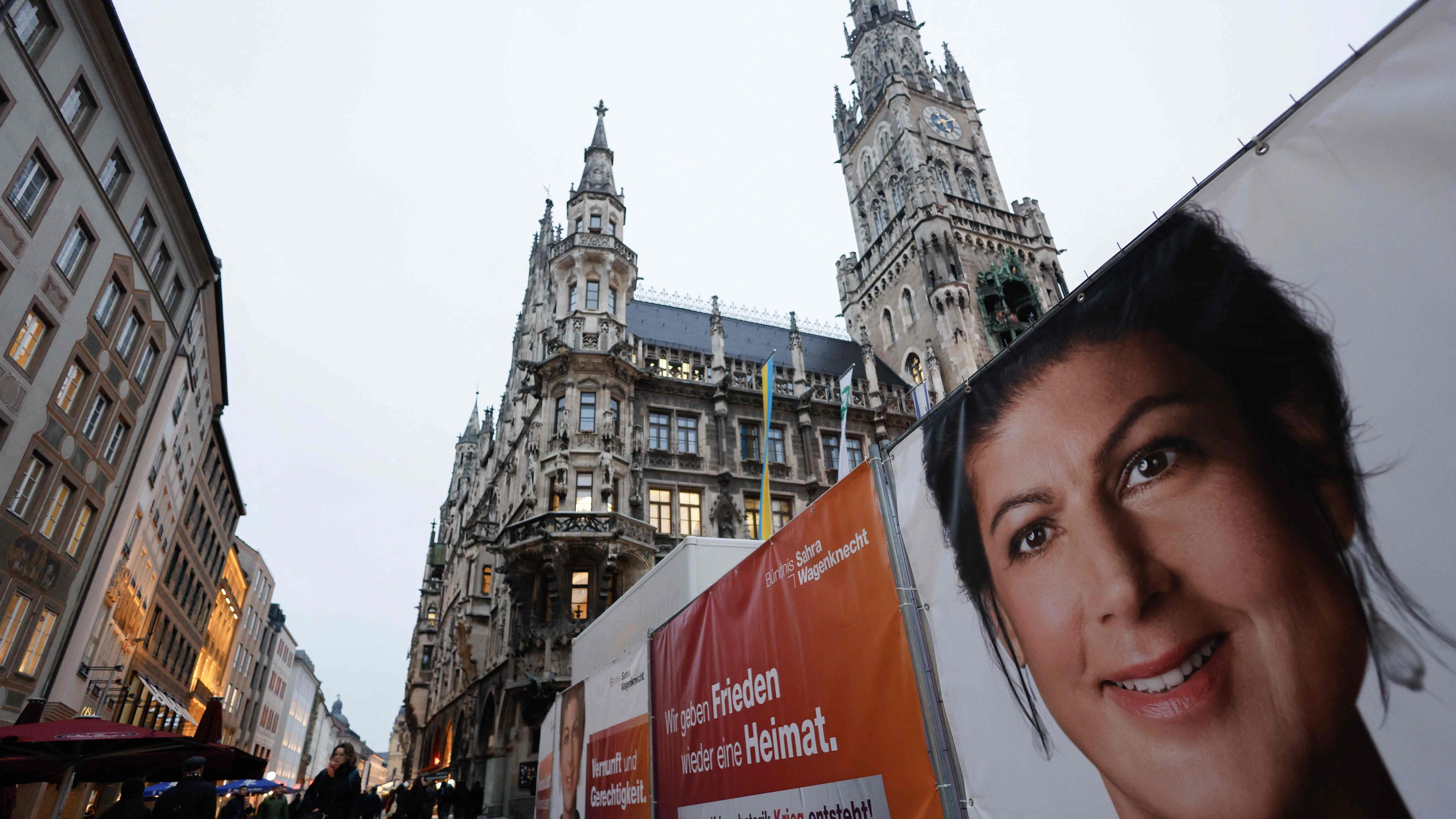 Menschen gehen an Plakaten vorbei, auf denen eine Wahlkampfveranstaltung mit der Vorsitzenden des linkspopulistischen Bündnisses Sahra Wagenknecht (BSW) angekündigt wird. Sahra Wagenknecht startet am 3. Februar 2025 auf dem zentralen Marienplatz in München den Wahlkampf der Partei.