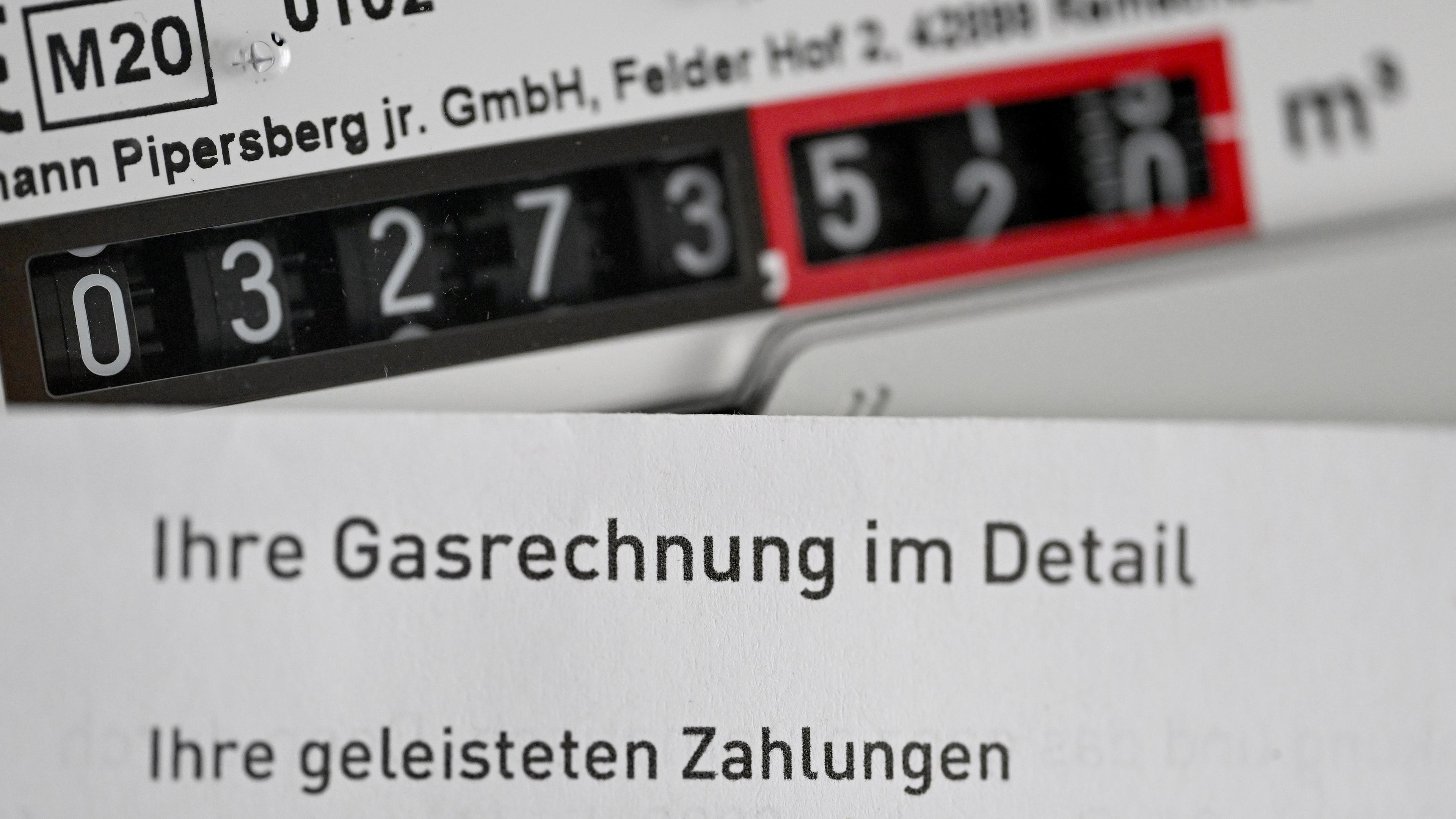 Eine Gasrechnung wird vor einen Gaszähler in einem privaten Haushalt gehalten