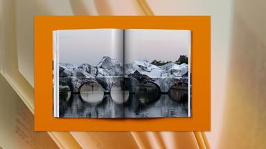 In einem aufgeschlagenen Buch ist ein Foto der verhüllten Pont Neuf Brücke in Paris zu sehen.