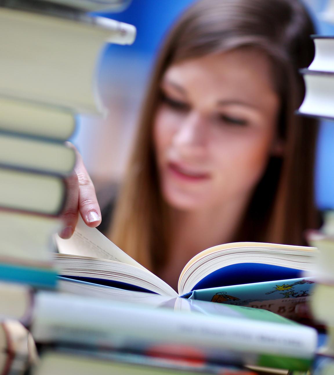 Frau liest hinter Bücherstapel
