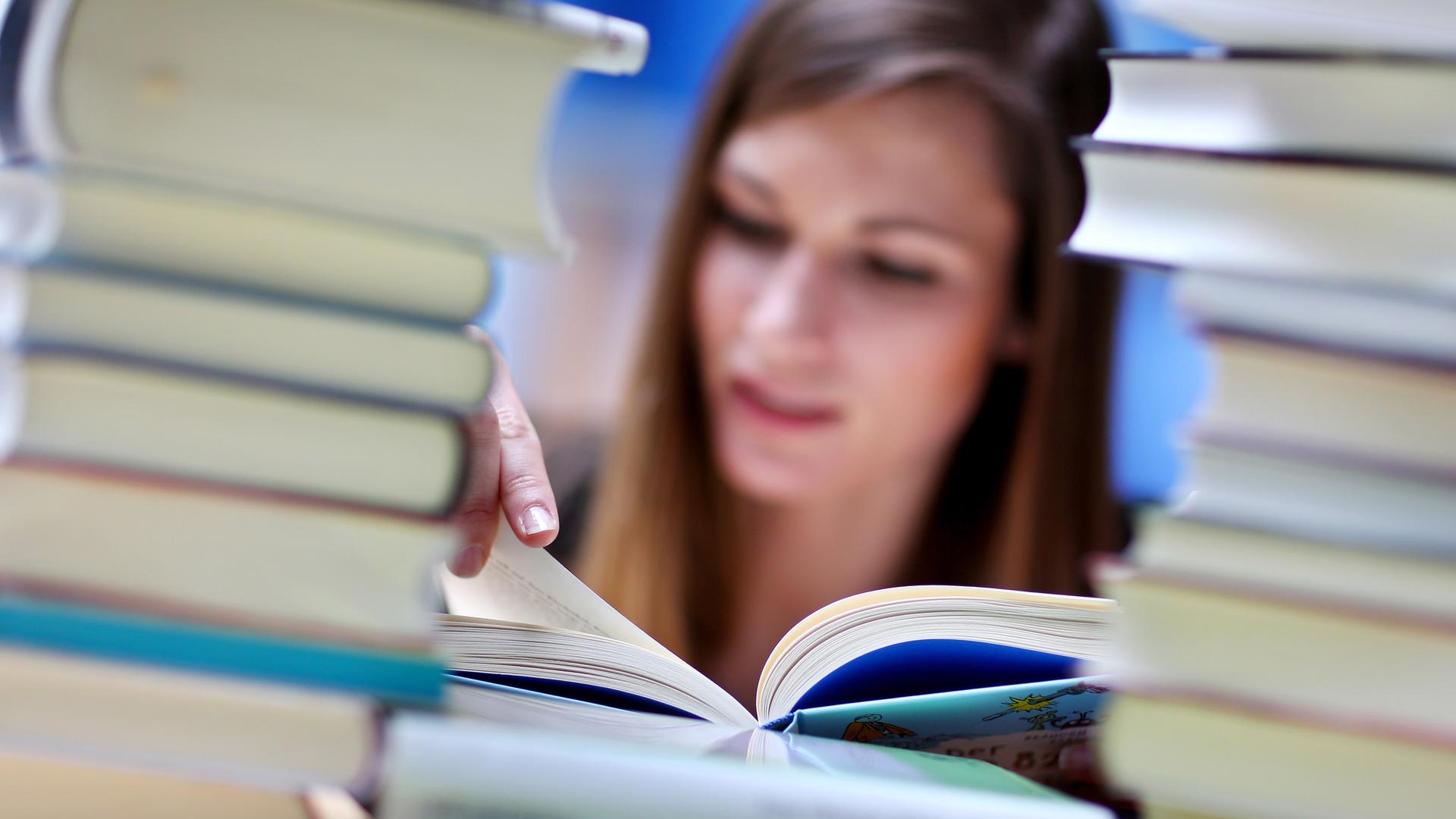 Frau liest hinter Bücherstapel