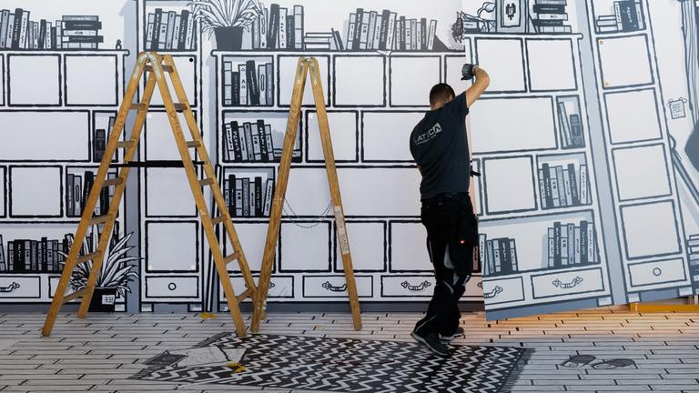 Messebauer errichten den Stand eines Buchverlages auf der Buchmesse.