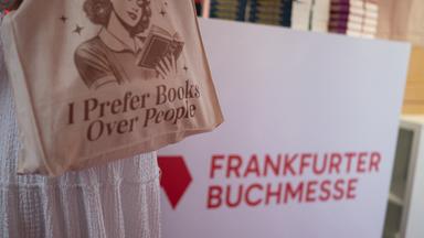 Eine Besucherin trägt eine Tasche mit der Aufschrift „I prefer books over people“. Das Logo der Frankfurter Buchmesse ist zu sehen.