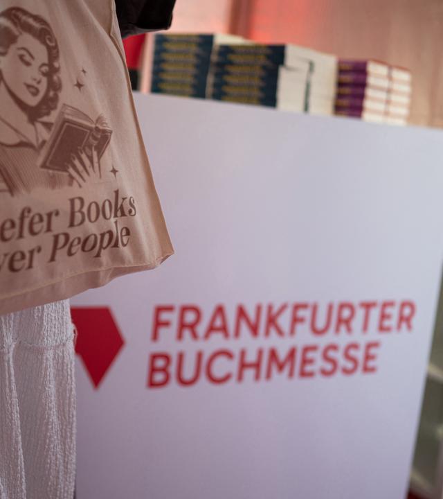 Eine Besucherin trägt eine Tasche mit der Aufschrift „I prefer books over people“. Das Logo der Frankfurter Buchmesse ist zu sehen.
