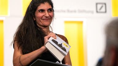 Die Gewinnerin des Deutschen Buchpreises 2026, Shida Bazyar, steht auf der Bühne.