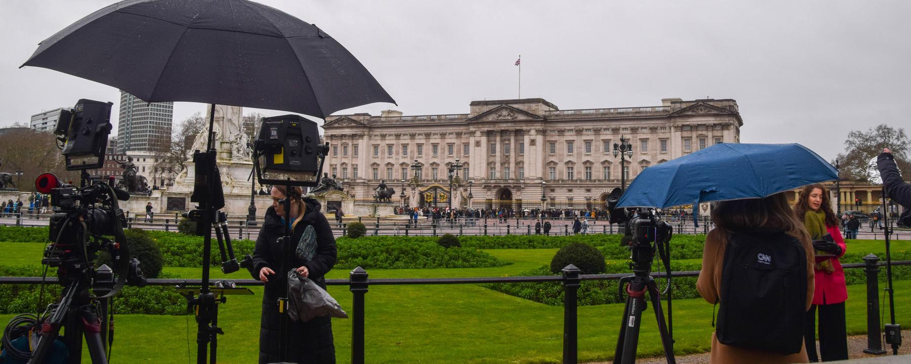 Pressevertreter versammeln sich mit Schirmen vor dem Buckingham Palace am 20.02.2026.