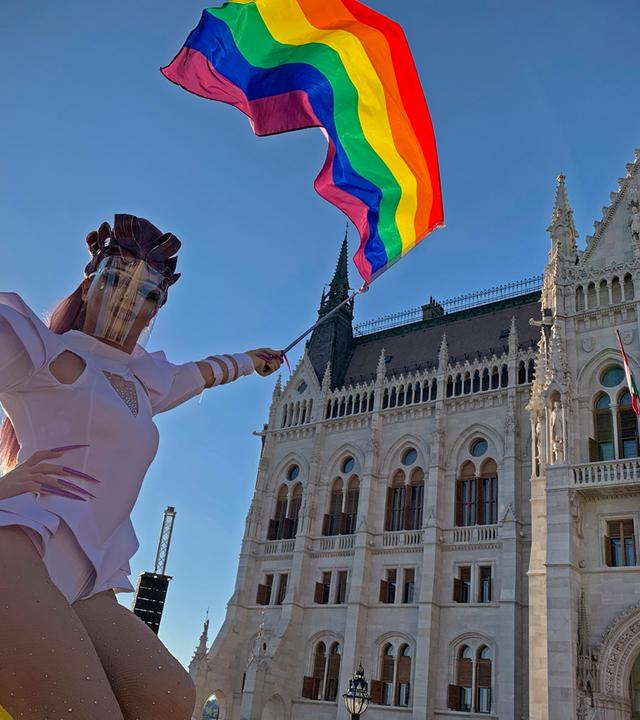 Ein Teilnehmer schwenkt am 14. Juni 2021 während einer Demonstration für LGBT-Rechte vor dem ungarischen Parlamentsgebäude in Budapest eine Regenbogenfahne.