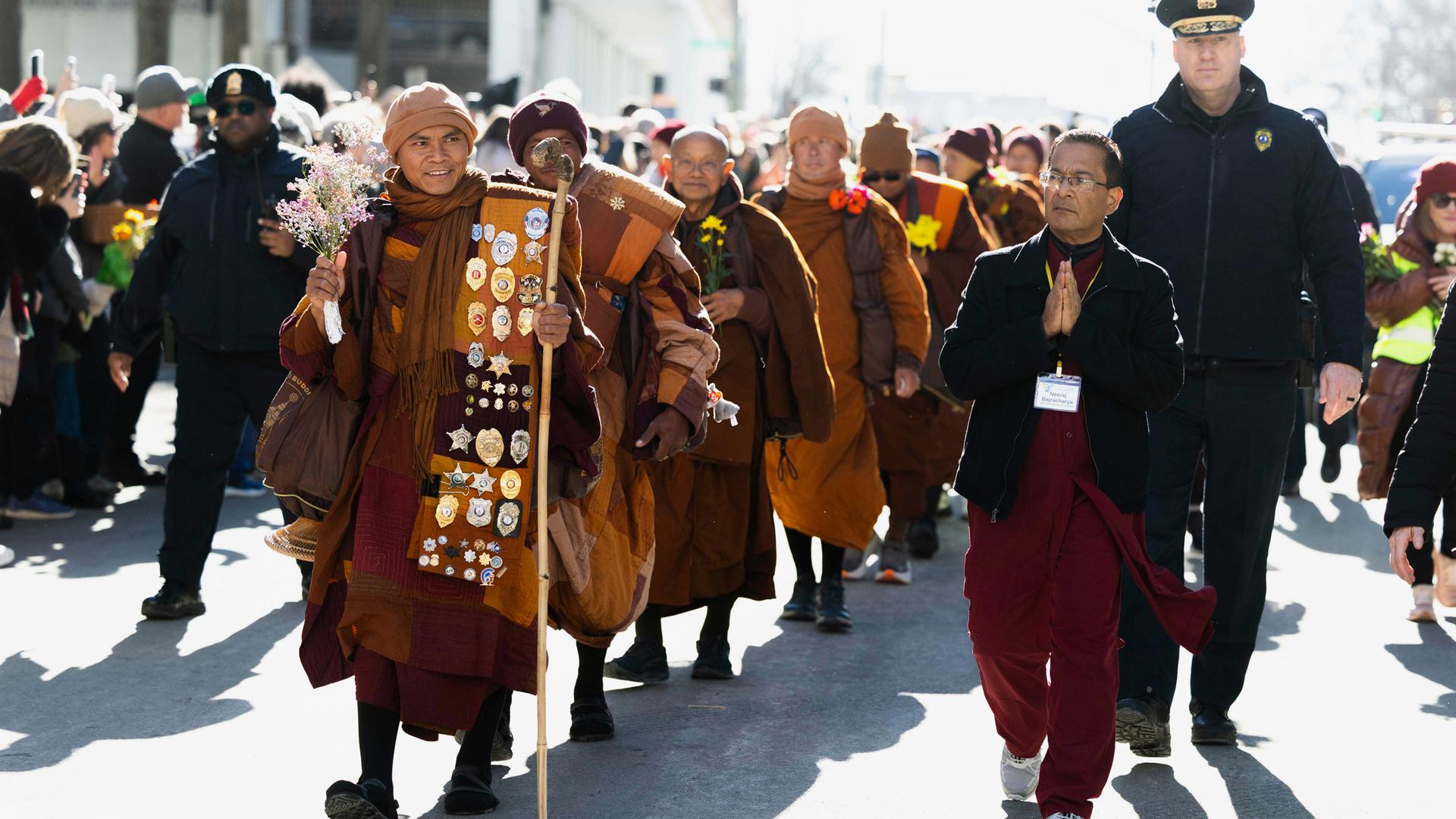 Einer der ehrwürdigen buddhistischen Mönche hält Blumen in der Hand, während sie für den Frieden in die Innenstadt von Richmond marschieren.