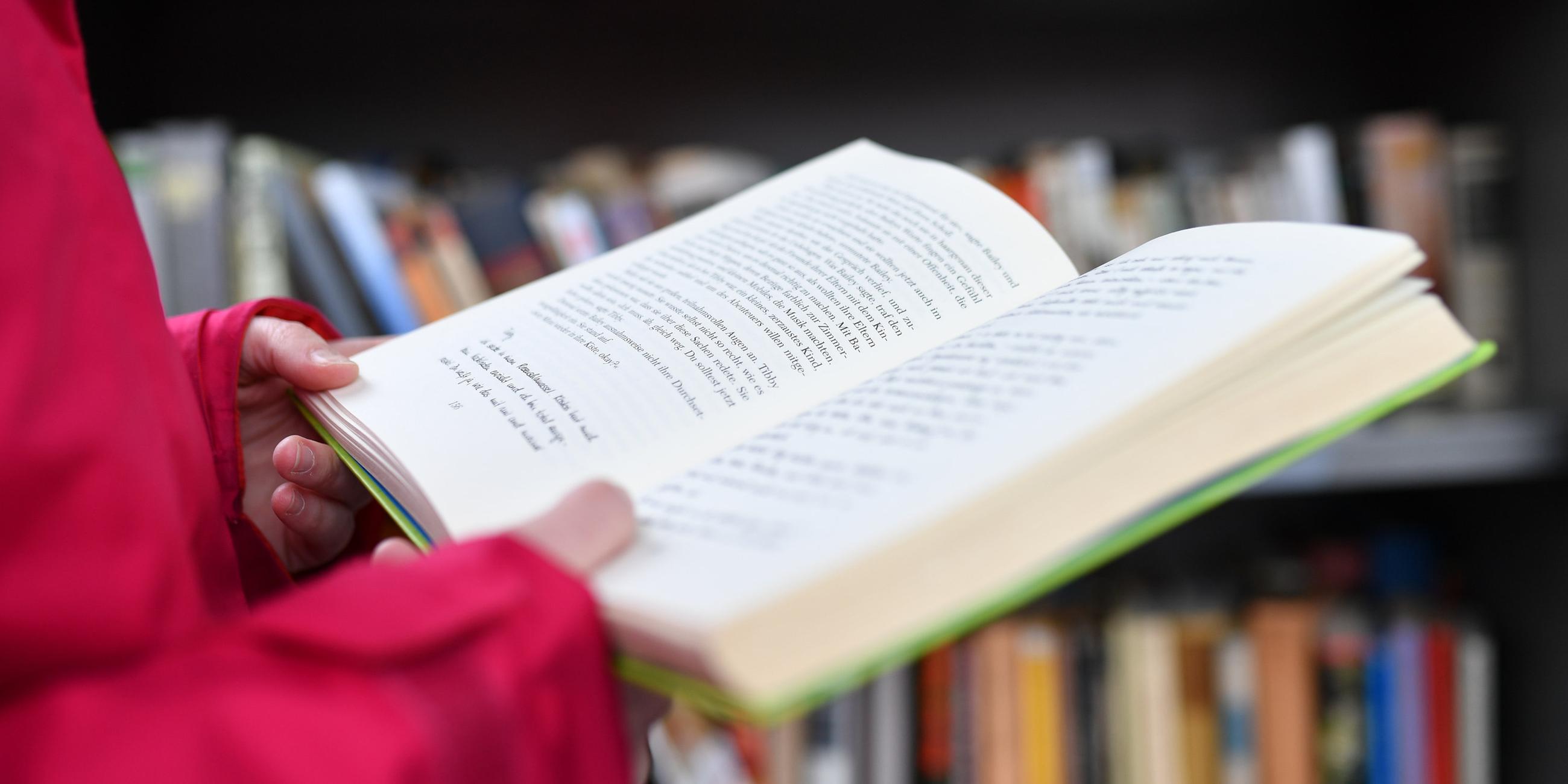 Eine Frau hält ein Buch in den Händen.