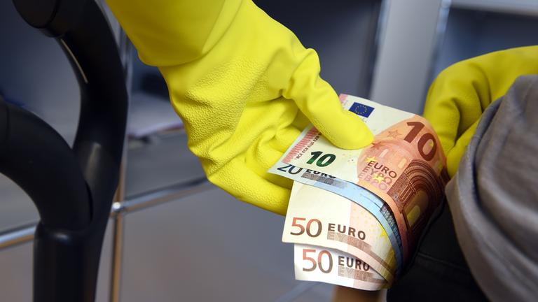 Eine Frau hält in einem Haus in Ravensburg mehrere Geldscheine in ihrer Hand.