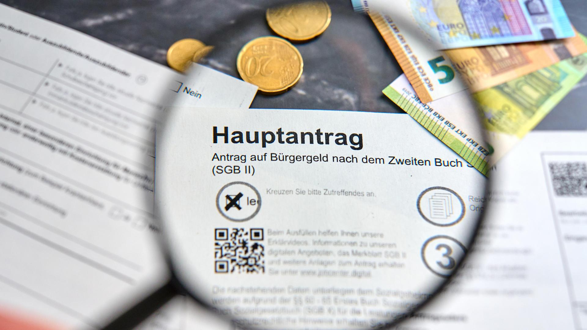 Hand hält Lupe über das Wort Bürgergeld auf dem Hauptantrag auf Bürgergeld der Agentur für Arbeit