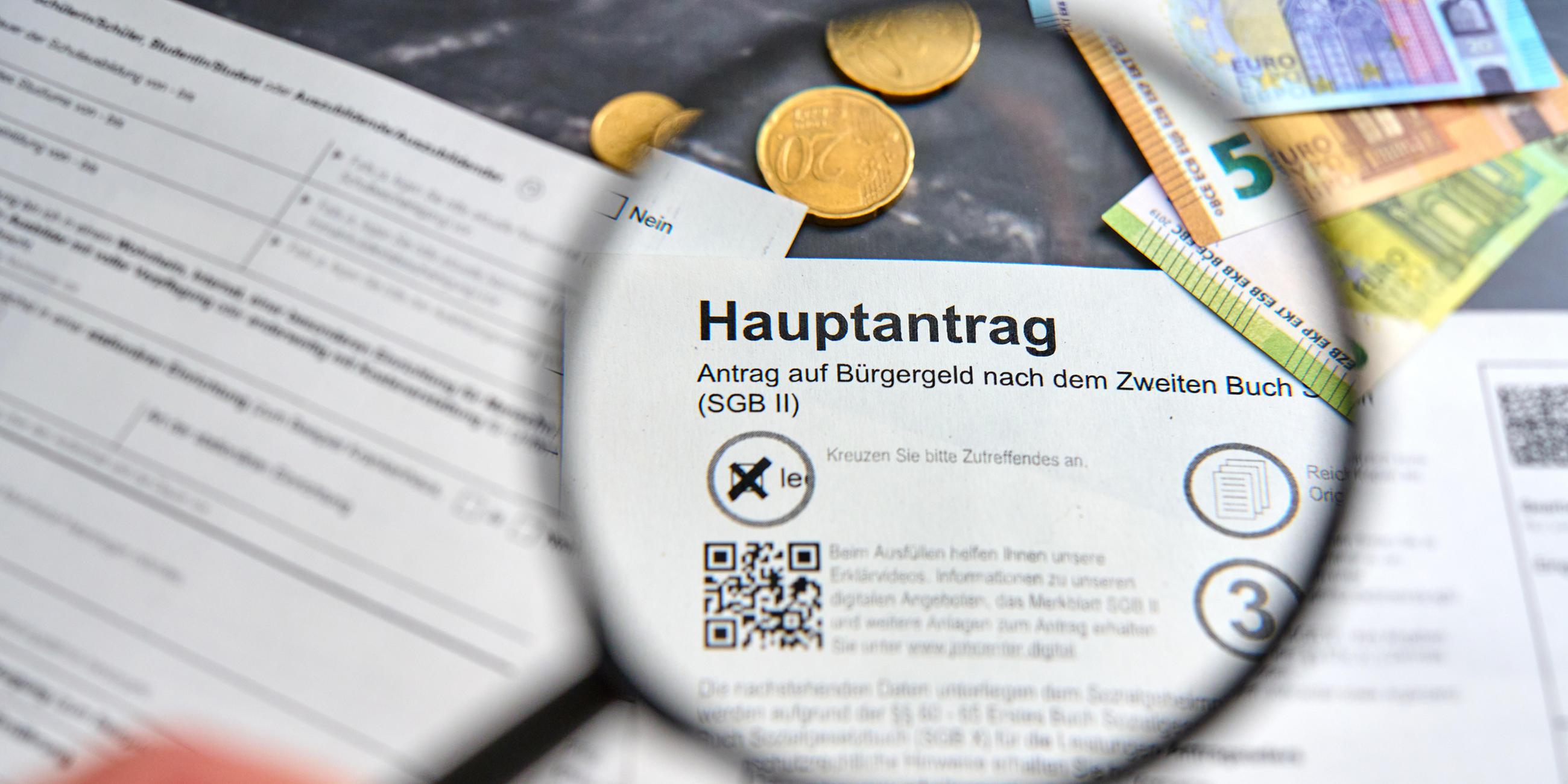 Hand hält Lupe über das Wort Bürgergeld auf dem Hauptantrag auf Bürgergeld der Agentur für Arbeit