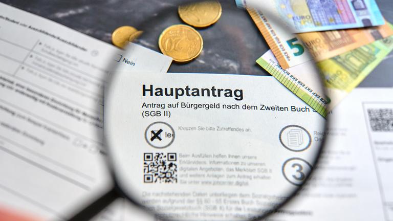 Hand hält Lupe über das Wort Bürgergeld auf dem Hauptantrag auf Bürgergeld der Agentur für Arbeit