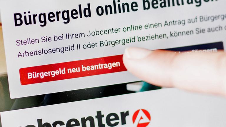 Berlin: Eine Frau tippt auf einem Tablet auf einen Link zum Beantragen des Bürgergeldes im Kundenbereich im Jobcenter Berlin Mitte.