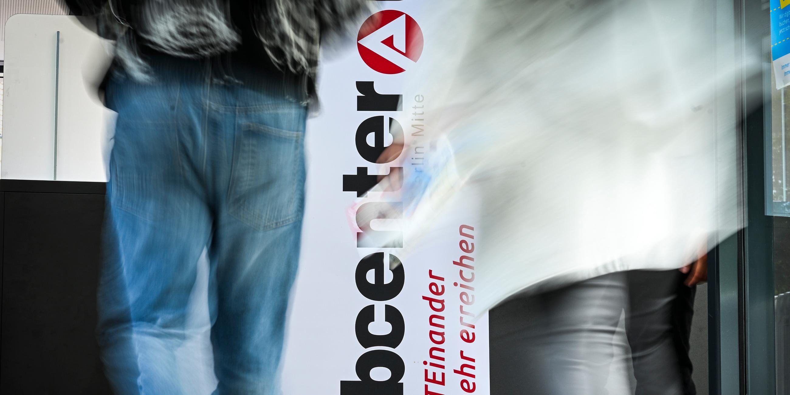 Personen gehen am Logo vom Jobcenter Berlin-Mitte bei der Jobmesse am 25.06.2025 vorbei. 