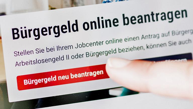 28.06.2023, Berlin: Eine Frau tippt auf einem Tablet auf einen Link zum Beantragen des Bürgergeldes im Kundenbereich im Jobcenter Berlin Mitte. 