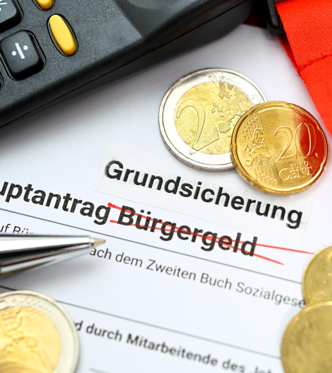 Hauptantrag Grundsicherung mit Geldmünzen auf einem Schreibtisch