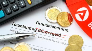 Hauptantrag Grundsicherung mit Geldmünzen auf einem Schreibtisch