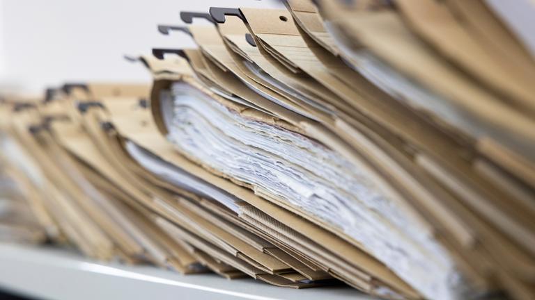 Symbolbild: Zahlreiche Akten sind auf einem Schreibtisch ausgelegt. 
