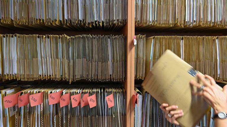 Hessen, Frankfurt/Main: Eine Mitarbeiterin einer Behörde greift an einem Regal nach einer Akte.