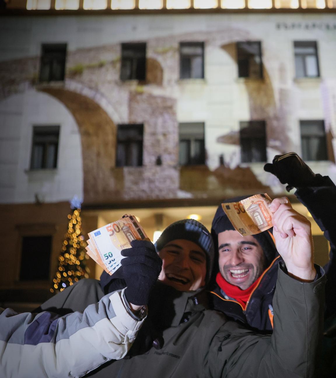 Menschen posieren mit Euro-Banknoten in der Hand, während sie das neue Jahr und die Einführung des Euro in Bulgarien vor der Bulgarischen Nationalbank feiern.