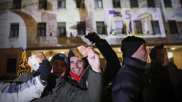 Menschen posieren mit Euro-Banknoten in der Hand, während sie das neue Jahr und die Einführung des Euro in Bulgarien vor der Bulgarischen Nationalbank feiern.