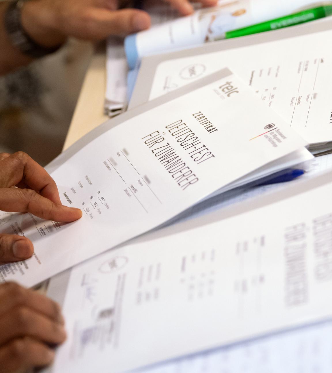 Bayern, München: Auf einem Tisch liegen mehrere Zertifikate mit der Aufschrift "Deutsch-Test für Zuwanderer".