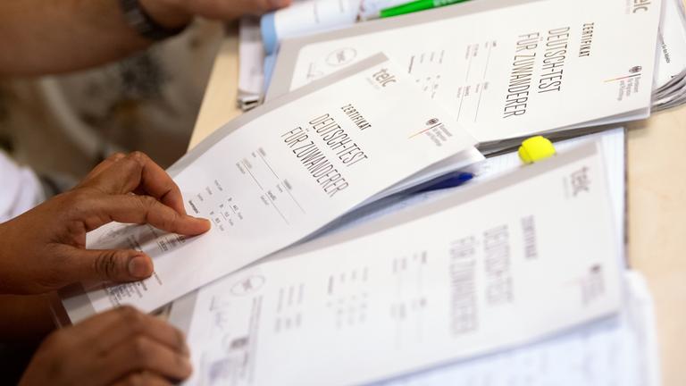 Bayern, München: Auf einem Tisch liegen mehrere Zertifikate mit der Aufschrift "Deutsch-Test für Zuwanderer".