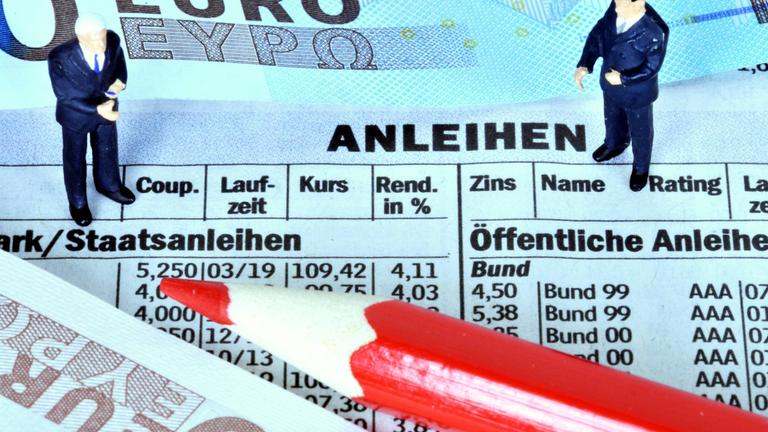 Ein Buntstift und ein Geldschein liegen auf dem Börsenteil einer Zeitung.