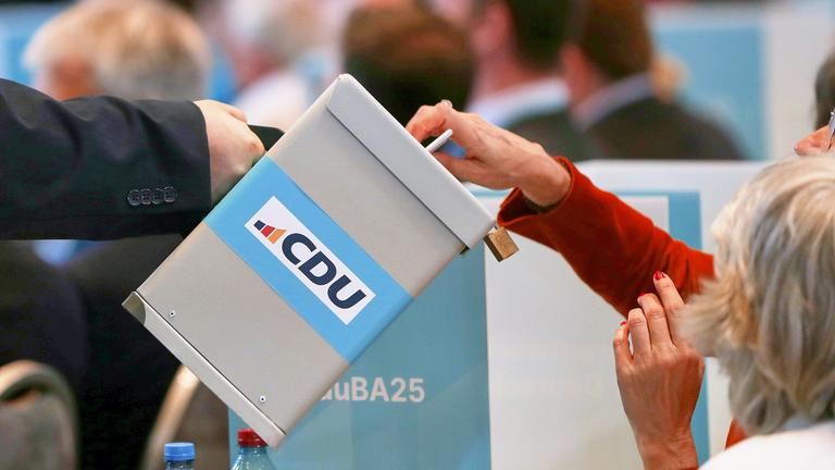 CDU-Bundesausschuss: Delegierte werfen eine Stimmkarte in eine Wahlurne