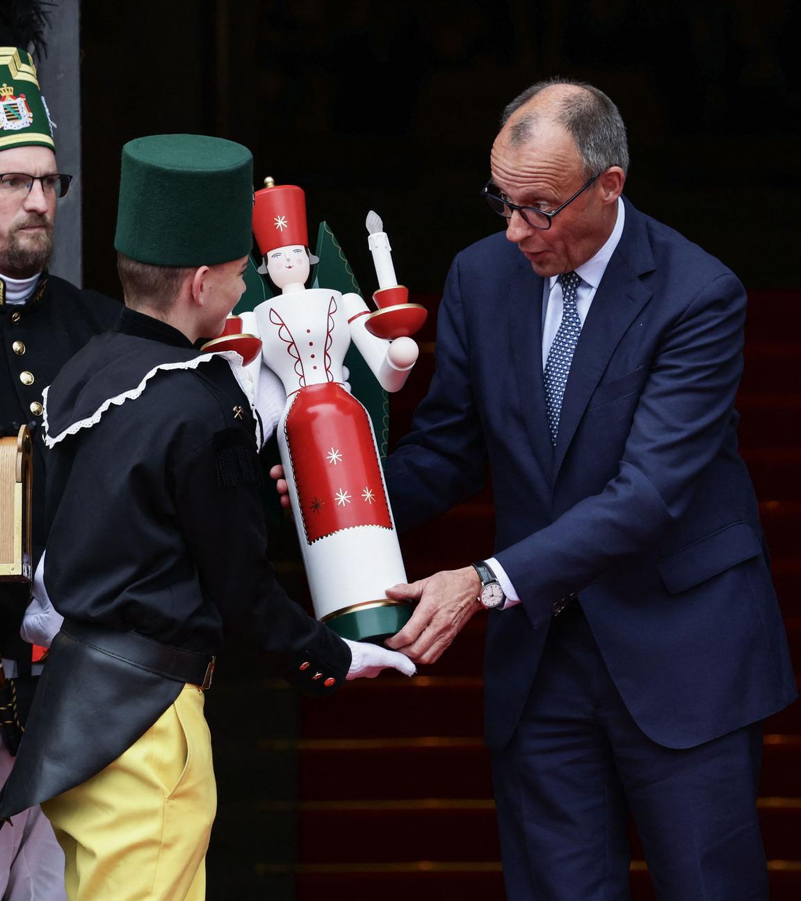 Sachsen, Dresden: Bundeskanzler Friedrich Merz (Mitte) erhält vom Bergmannsmusikkorps einen traditionellen hölzernen Kerzenständer überreicht