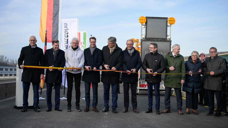 NRW-Ministerpräsident Hendrik Wüst (4. v. l.), Bundesverkehrsminister Patrick Schnieder (5. v. l.) und Kanzler Friedrich Merz (5. v. r.) durchschneiden das Band bei der Eröffnung der Rahmedetalbrücke bei Lüdenscheid.