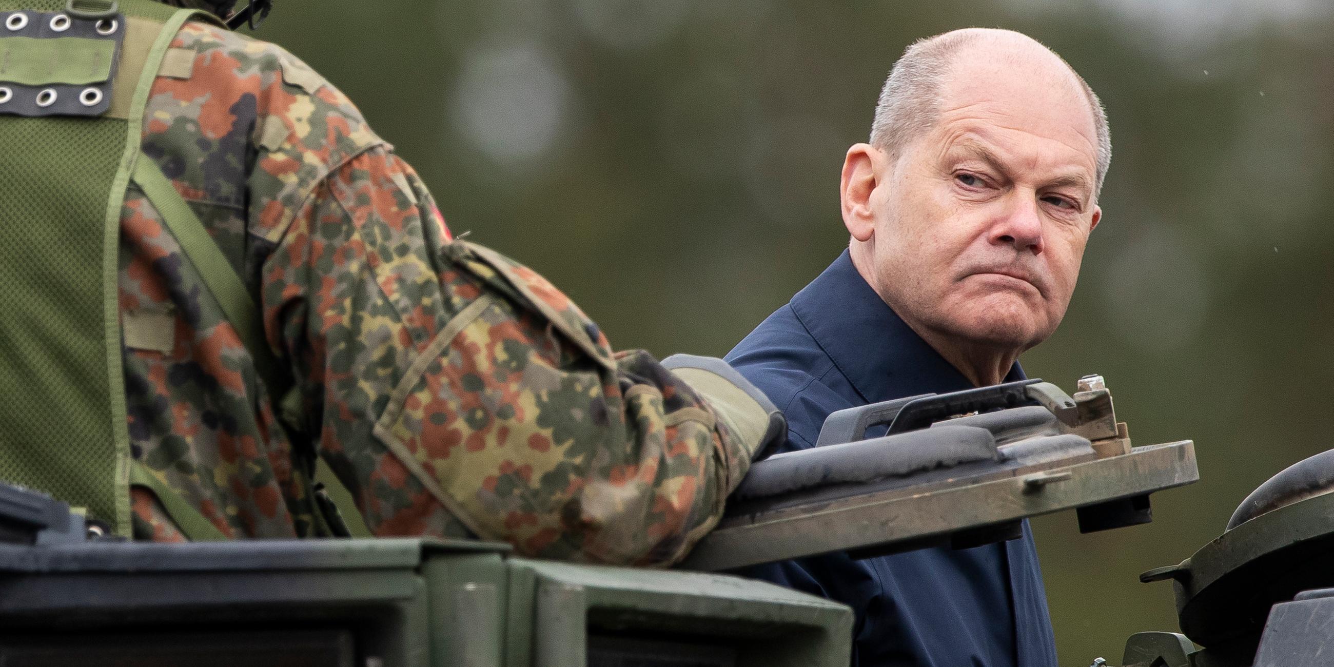 Litauen, Vilnius: Bundeskanzler Olaf Scholz (SPD) fährt auf einem gepanzerten Militärfahrzeug während der litauisch-deutschen Militärübung "Grand Quadriga" auf einem Truppenübungsplatz in Pabrade.