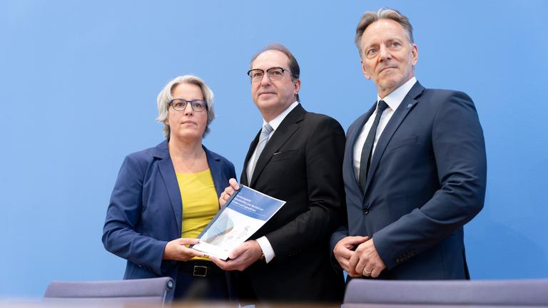 Kerstin Claus, Alexander Dobrindt und Holger Münch halten bei der Bundespressekonferenz den Bericht in der Hand