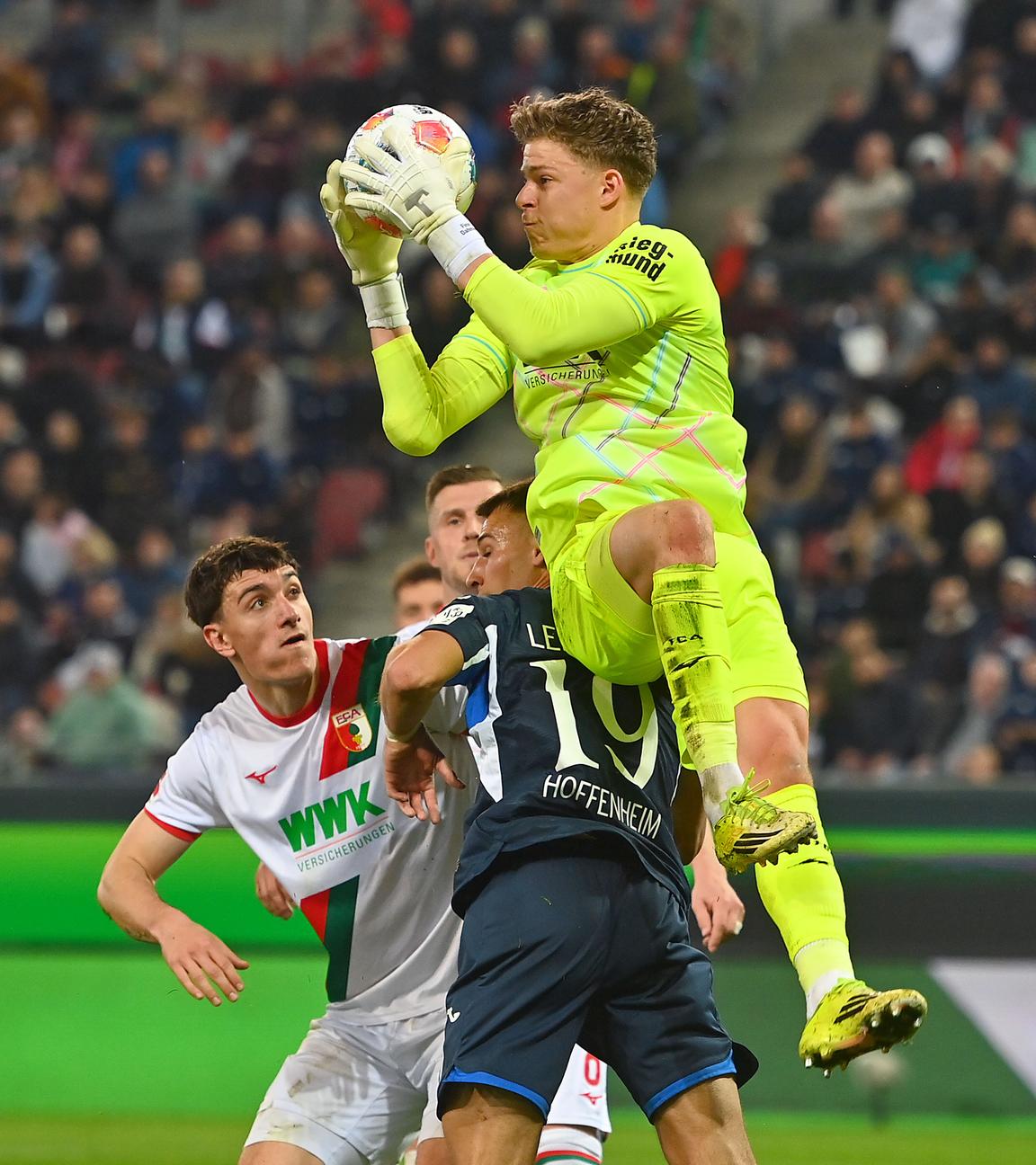 Torwart Finn Dahmen (FC Augsburg) im Zweikampf gegen Tim Lemperle (1899 Hoffenheim) am 10.04.2026 in Augsburg.