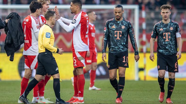 Leroy Sane und Joshua Kimmich von Bayern München reagieren auf das Ergebnis am Ende der Spielzeit, während Berlins Diogo Leite, Tom Rothe und Danilho Doekhi jubeln.